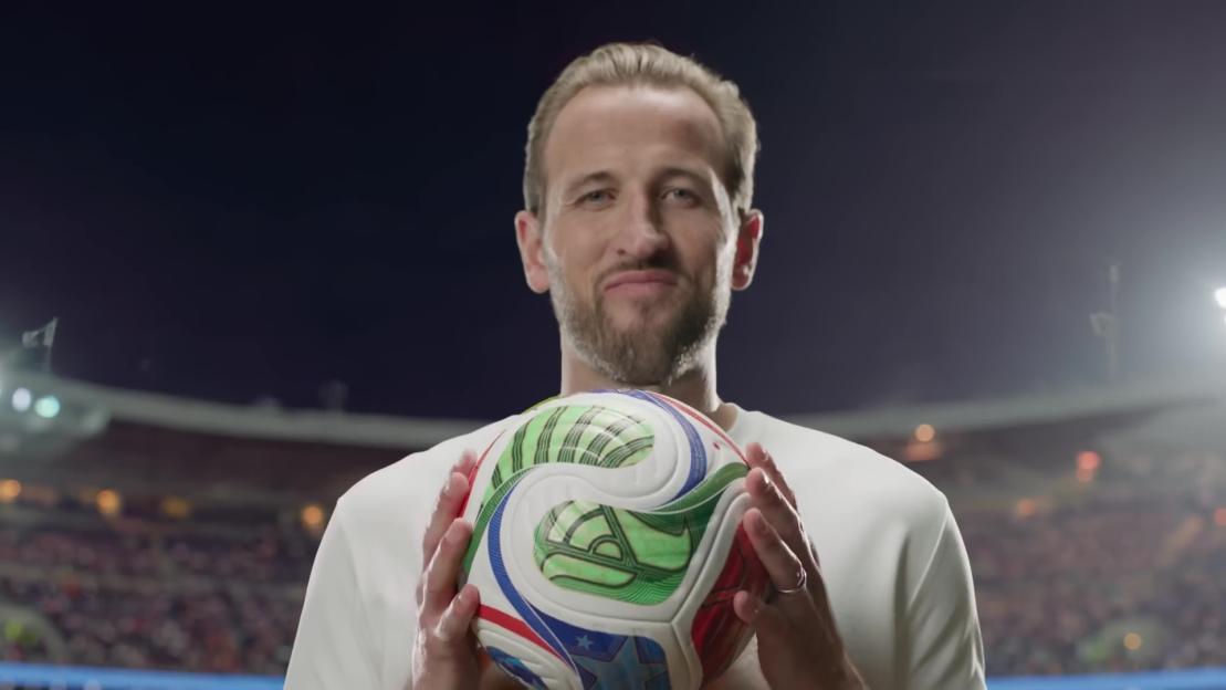 Man holding a multicolored soccer ball in a stadium.