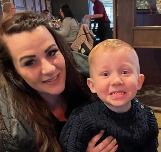 Faye Knowles smiling while holding a young boy.