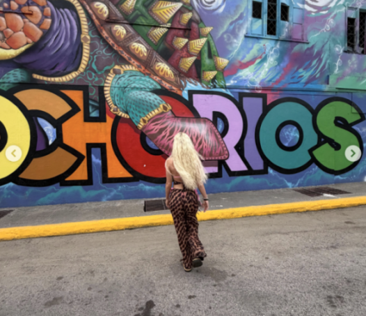 Woman walking away from a colorful mural that spells "Ocho Rios."