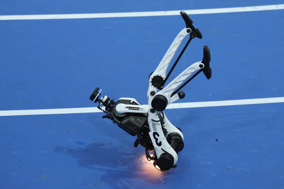 A robot fell and caught fire on a blue track after crossing the finish line.