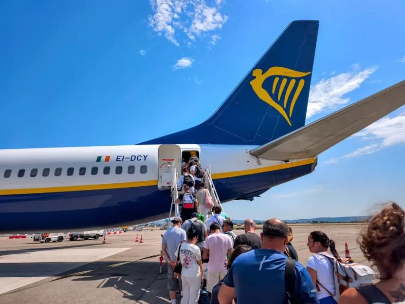 Passengers boarding a Ryanair airplane via stairs on the tarmac.