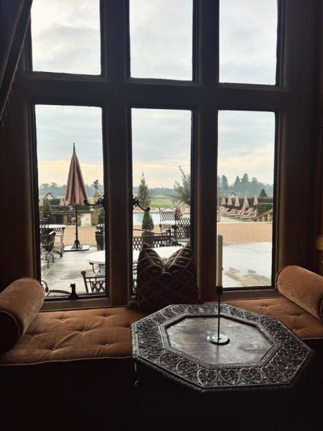 Window with a view of an outdoor dining area with umbrellas and lounge chairs.