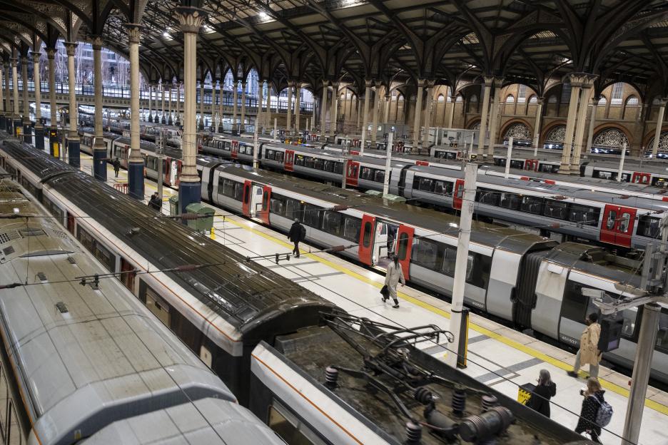 Commuters on platforms next to multiple trains inside Liverpool Street train station.
