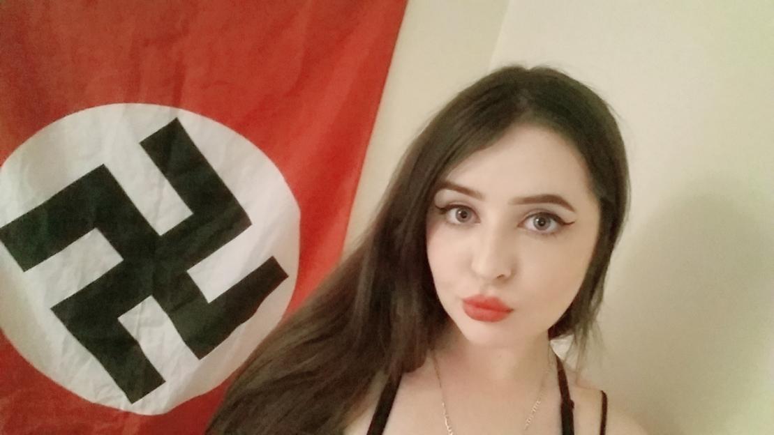 Alice Cutter posing in front of a Nazi flag.