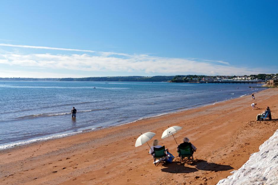 Elderly couple relaxing on Preston Sands, Paignton, Tor Bay, Devon, England.