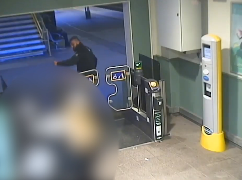 A man in a dark jacket attempting to pass through a subway turnstile, which appears to be malfunctioning.