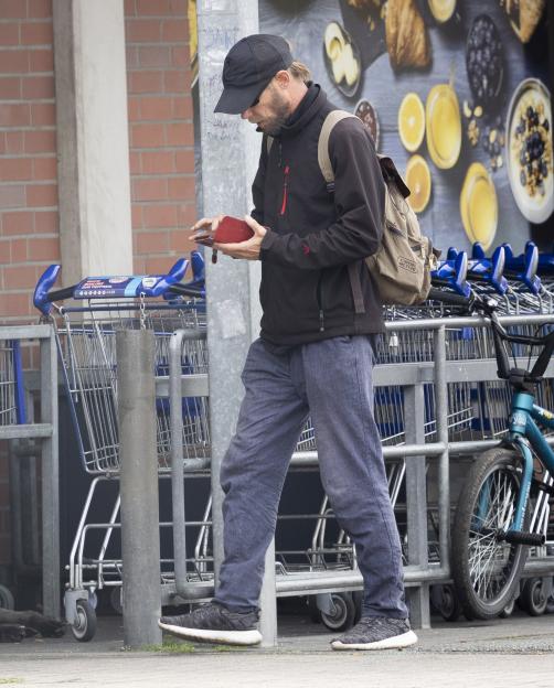 Christian Brueckner looking down at a red wallet in his hands while standing next to a line of shopping carts.