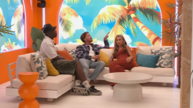 Three people on a white sectional couch with palm tree wallpaper and orange walls in the background.
