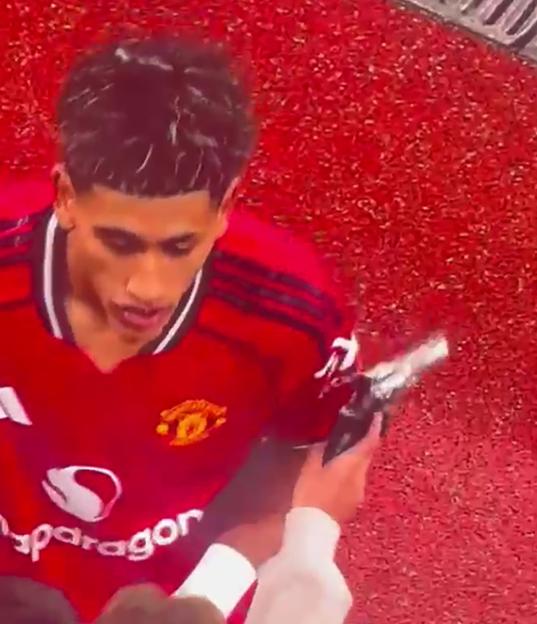 A young man in a red jersey holding a gun.