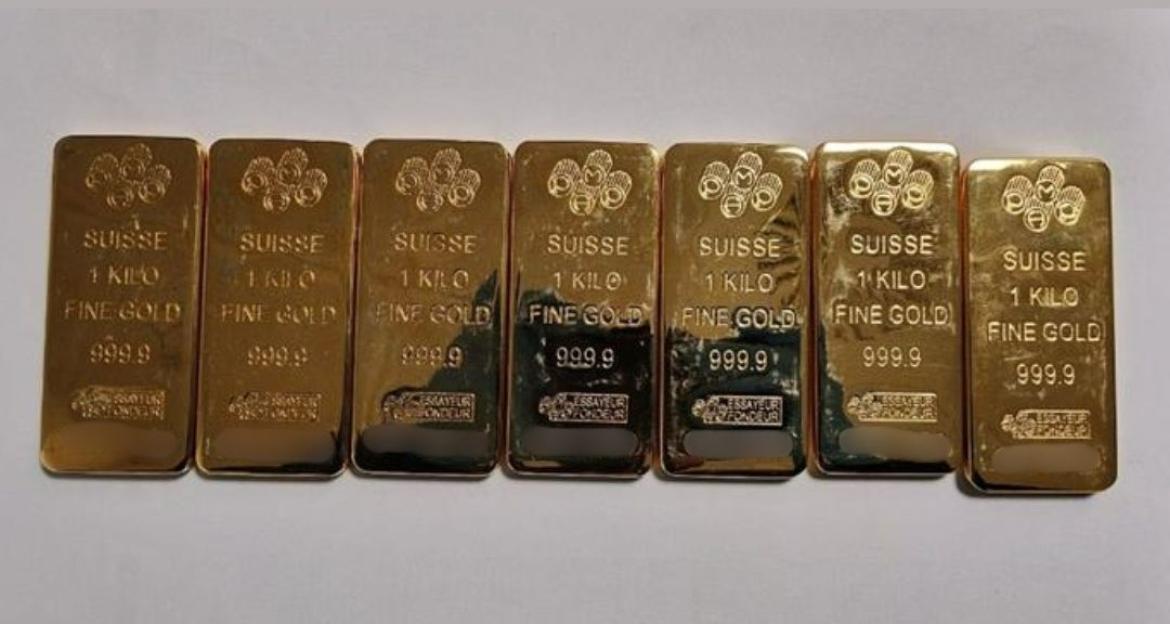 Seven 1-kilogram gold bars, marked "Suisse Fine Gold 999.9", seized in a money laundering investigation.