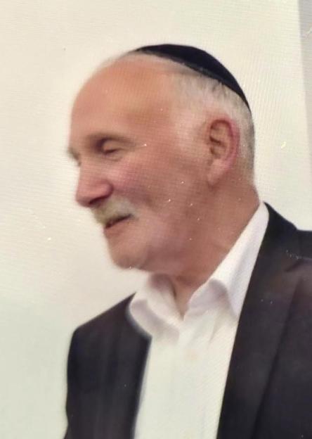 Headshot of Moshe Shine, a man with a mustache and a black kippah, looking to the side and smiling slightly.