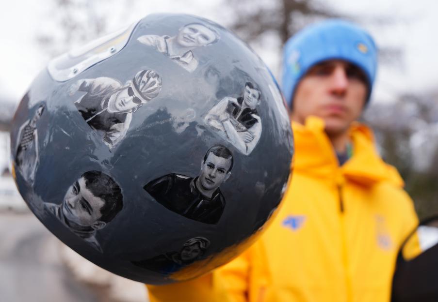 Close-up of Ukrainian skeleton athlete Vladyslav Heraskevych holding his helmet, which features painted portraits of people killed in the war with Russia.