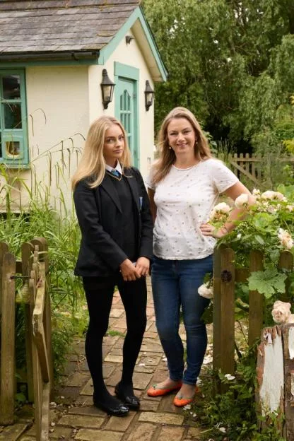 Sybilla Hart in her school uniform and her mother Beatrice Hart standing in a garden.