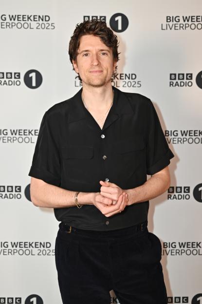 Sandra Bullock smiling, wearing a purple strapless gown, holding a Golden Globe award.