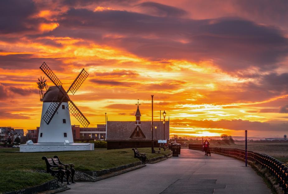 Sunrise over Lytham windmill with vibrant orange and purple clouds.