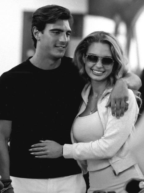 Black and white photo of a man with his arm around a smiling woman wearing sunglasses.