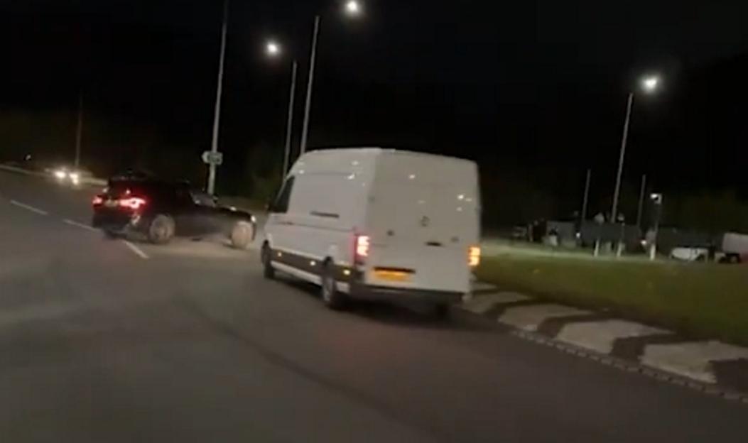 Black BMW X3M Competition drifting around a roundabout at night.
