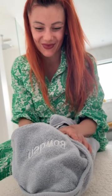 Dianne Buswell in green pajamas, holding a baby wrapped in a gray towel with "Bowden" embroidered on it.