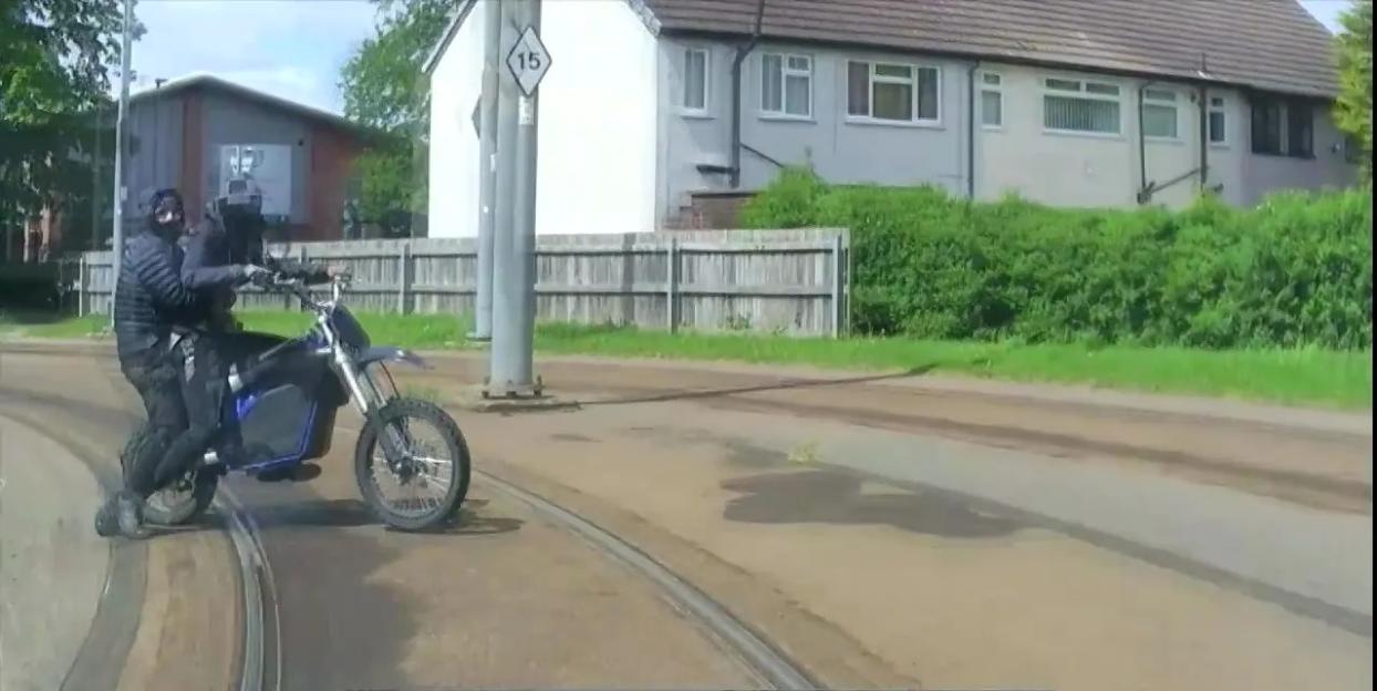 Two people on an e-bike being rammed by a police vehicle after a chase along tram tracks.