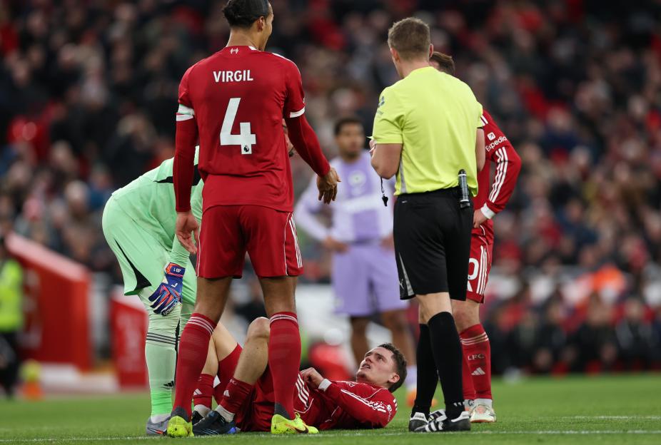 Liverpool FC player Florian Wirtz lying on the ground after a tackle during a soccer match.