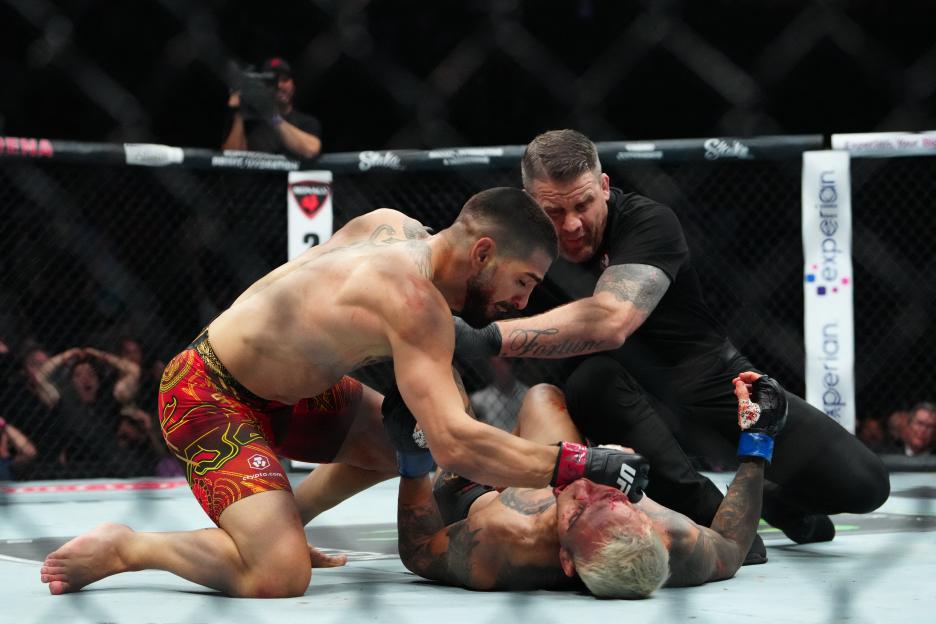 Ilia Topuria (red gloves) fighting Charles Oliveira (blue gloves) in a UFC match.