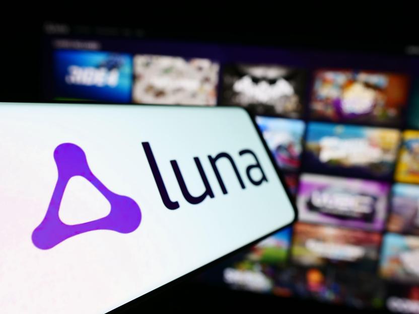 The Luna gaming platform logo and name displayed on a phone, with a blurred background of various game titles.