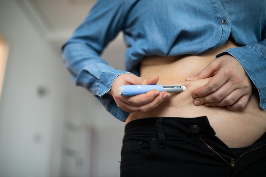 A woman self-injects insulin into her abdomen.