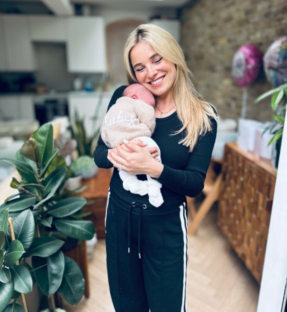 Sian Welby holding her baby, whose name is revealed as Rudy on the baby's sweater.
