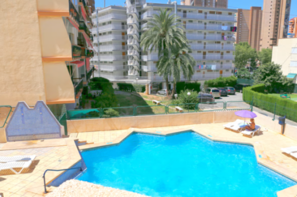 Swimming pool at LFM Dynastic Apartments, with buildings and palm trees in the background.