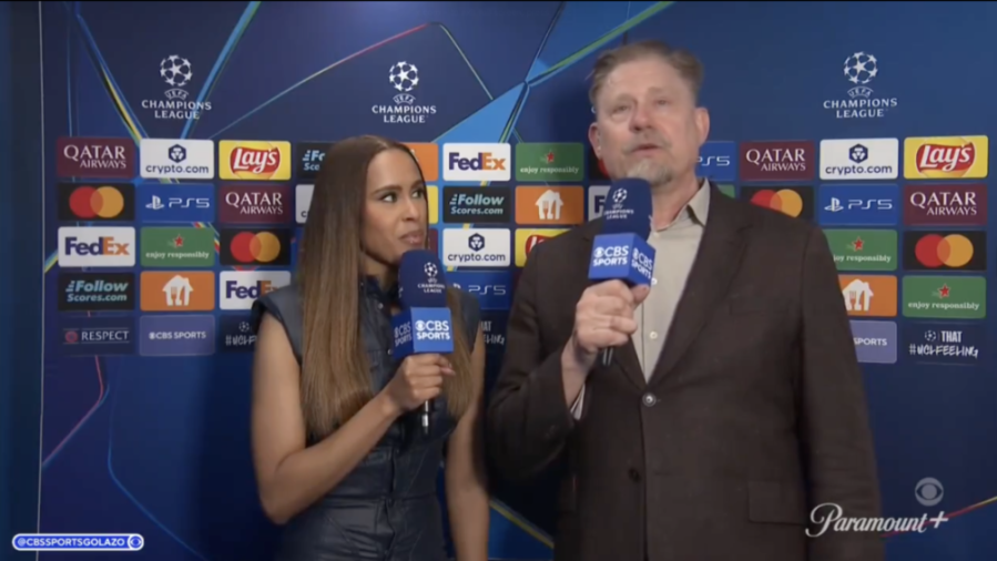 A man and a woman speaking into CBS Sports microphones in front of a Champions League backdrop with sponsor logos.