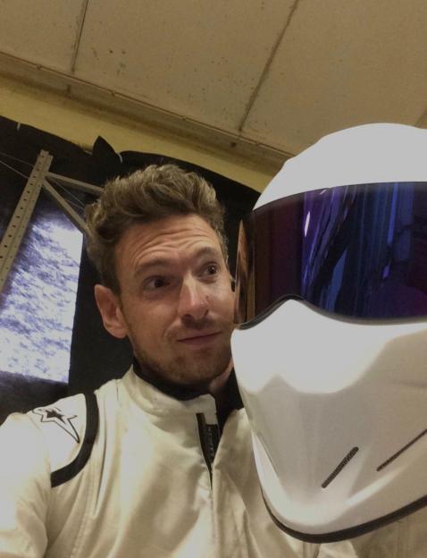 Racing driver and Stig driver for Top Gear Paul Rees in a white racing suit holding a white racing helmet.