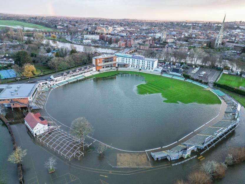 Aerial view of Worcestershire Cricket Ground largely flooded, with only parts of the grass pitch visible.