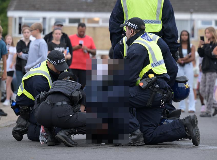 Police officers making an arrest in Thetford amidst protests.