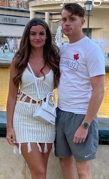 Couple posing together near a fountain.