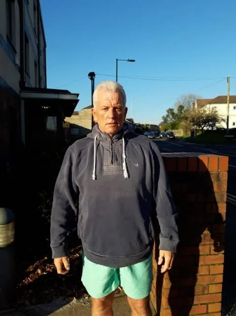Clifford Foster standing outdoors wearing a blue hoodie and green shorts.