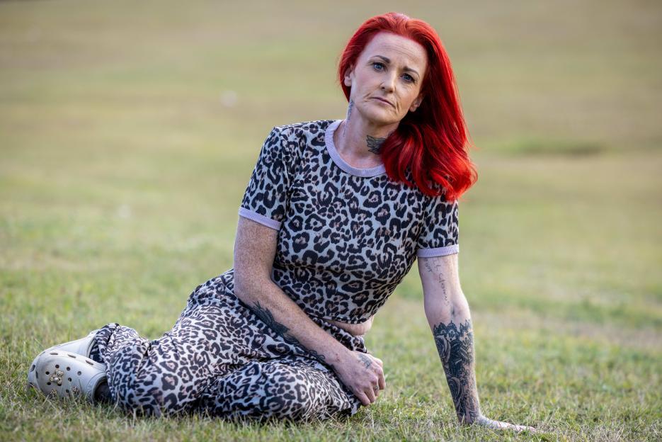 Zoe Johnson, who found out her ex-boyfriend had been drugging and raping her after they split up, sits on the grass.