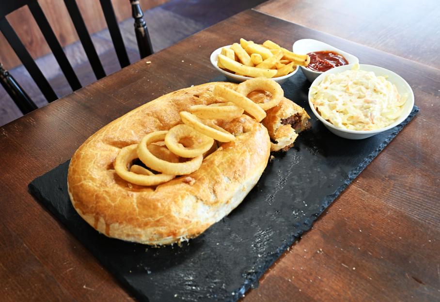 A 4-foot sausage roll topped with onion rings, served with chips, ketchup, and coleslaw.