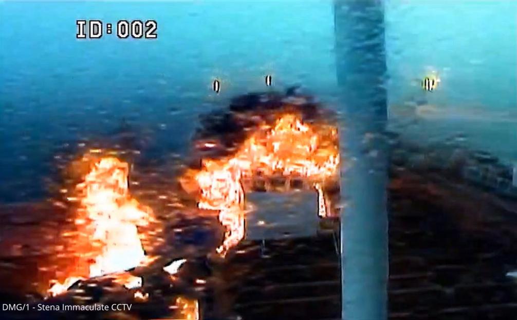 CCTV footage shows a vessel on fire in the water, with large flames consuming part of its structure.