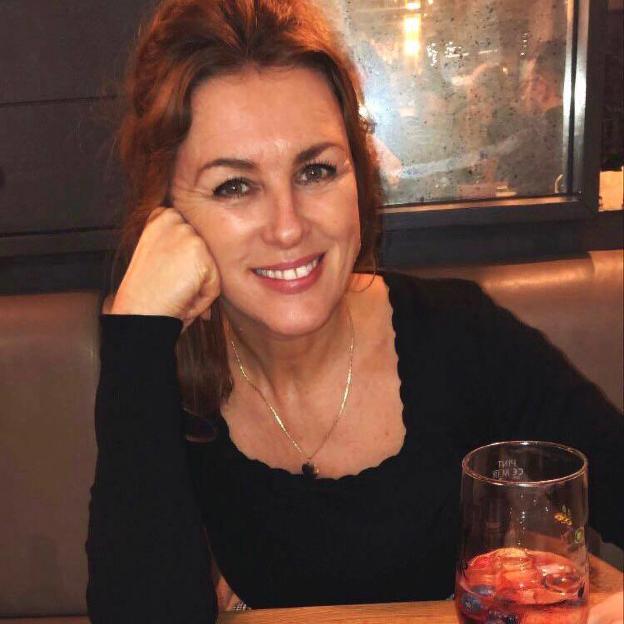 Trudi Burgess, a teacher, in a black top, smiling.