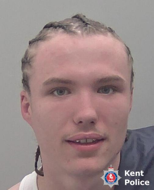 Mugshot of a young man with braided hair, light eyes, and a slight mustache, with a Kent Police logo in the lower right corner.