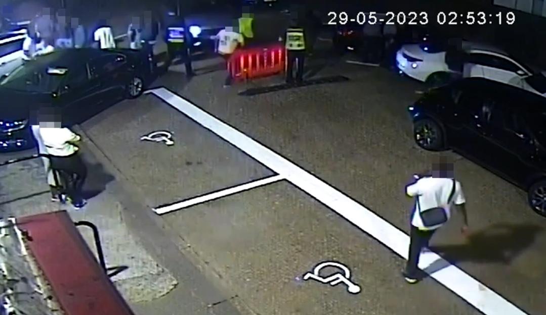 CCTV footage captures a dark parking lot with people, cars, and a red barrier.