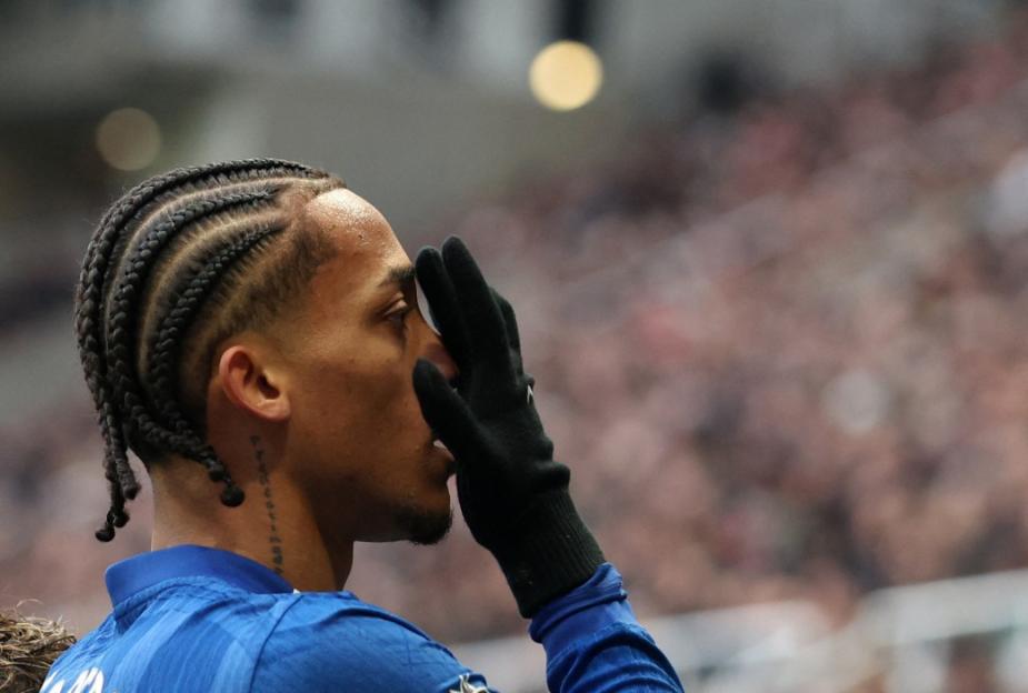 A Chelsea player with braided hair and a black glove over his face on the field.