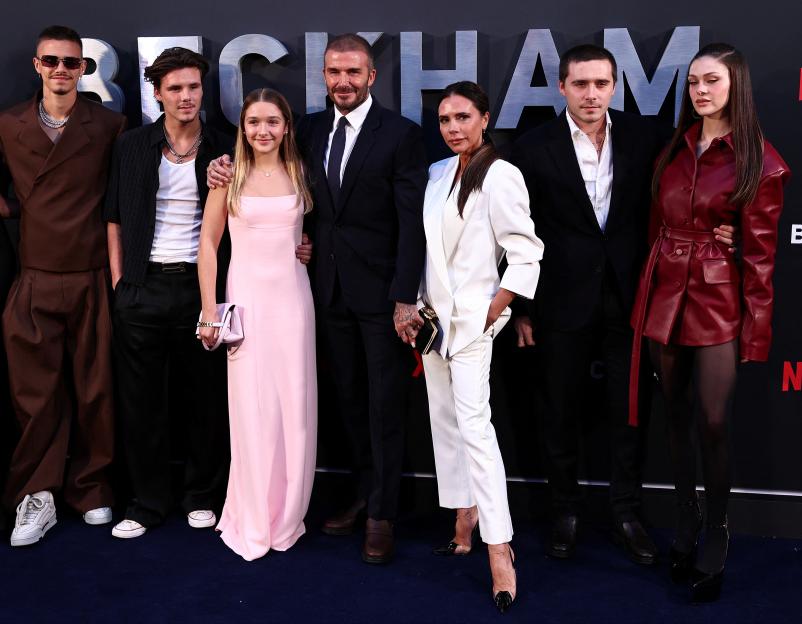 David and Victoria Beckham with their children and partners on a red carpet.