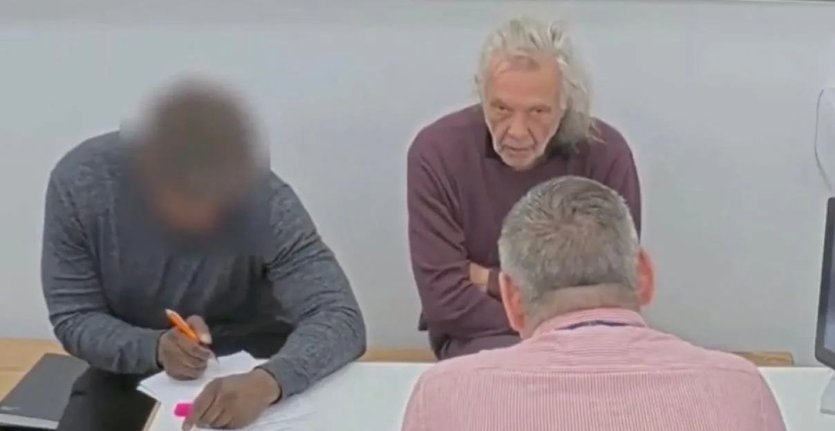 Melvin West, aged 73, sitting at a desk with two other people.