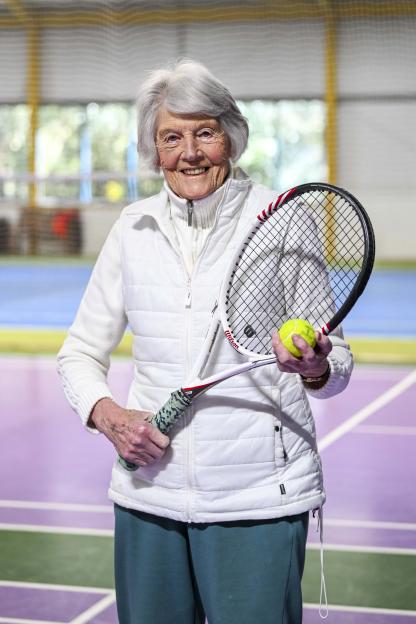Shirley Critchley, Britain's oldest female tennis player, smiling while holding a tennis racket and a tennis ball.