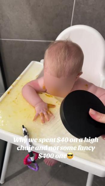A baby sitting in a high chair, playing in spilled food and water.