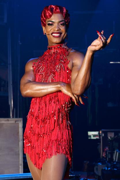 Johannes Radebe in a sparkling red dress and red wig at the Kinky Boots photocall.