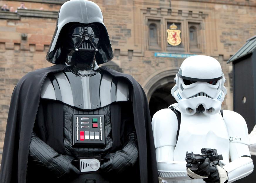 Darth Vader and a Stormtrooper in costume stand outside Edinburgh Castle.