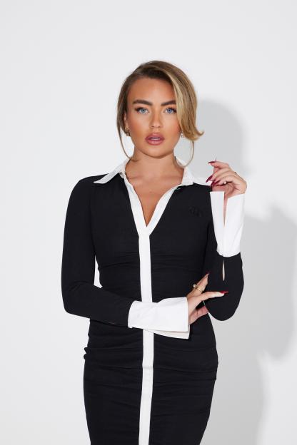 Ella Rae Wise posing in a black dress with white lapels and cuffs.