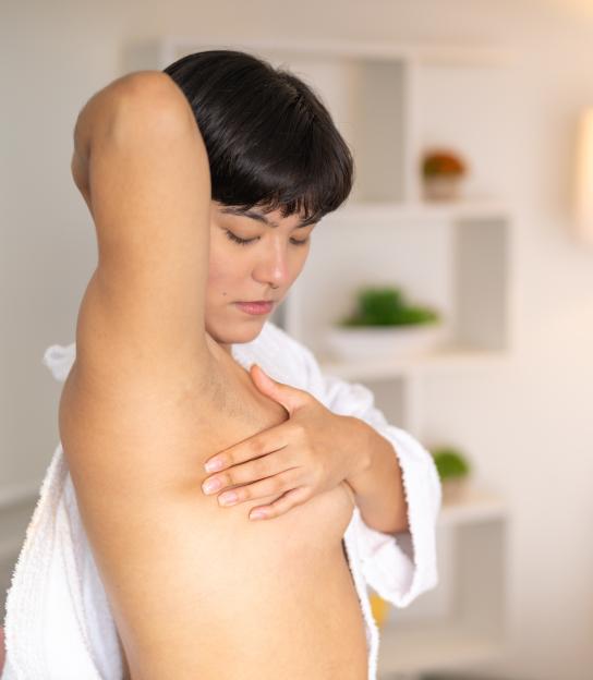 Woman touching her breast to check it at home.